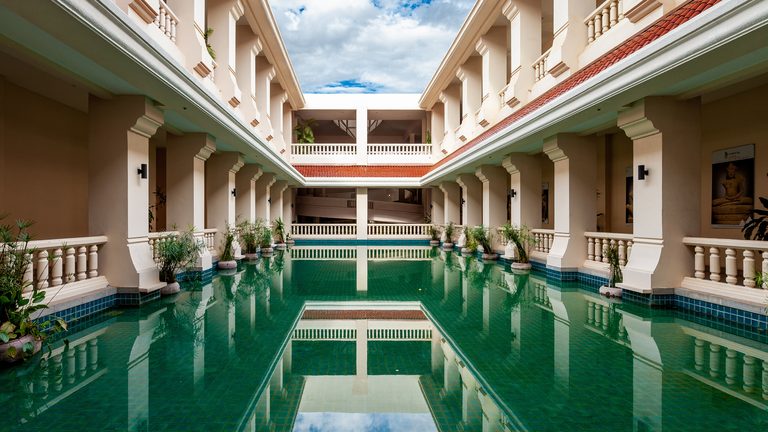 Colonnaded galleries and a green reflecting pool in the Angkor National Museum courtyard.